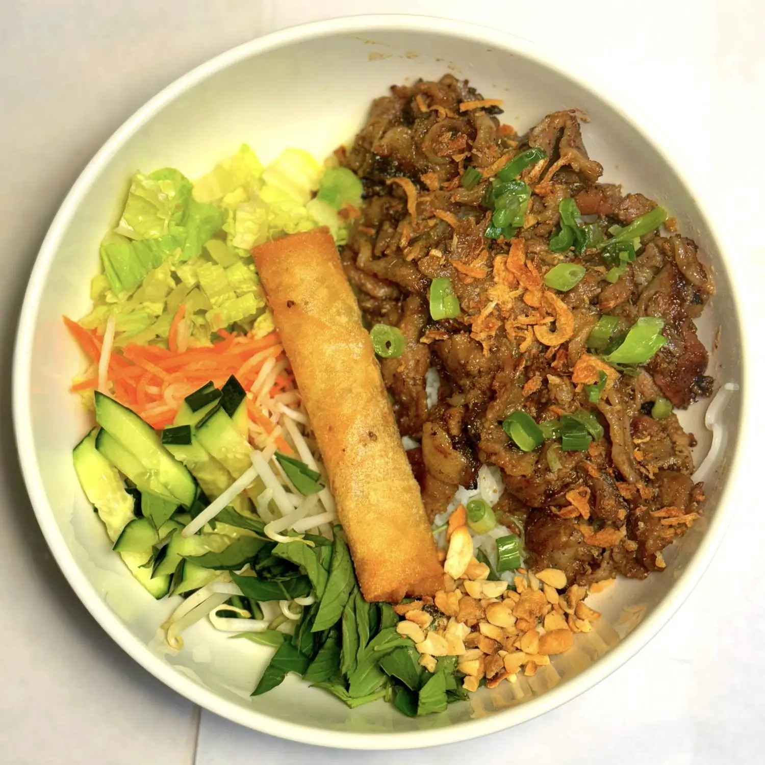 Vietnamese bowl with grilled meat, egg roll and fresh veggies at Magnolia Pho, a Vietnamese Restaurant in Seattle