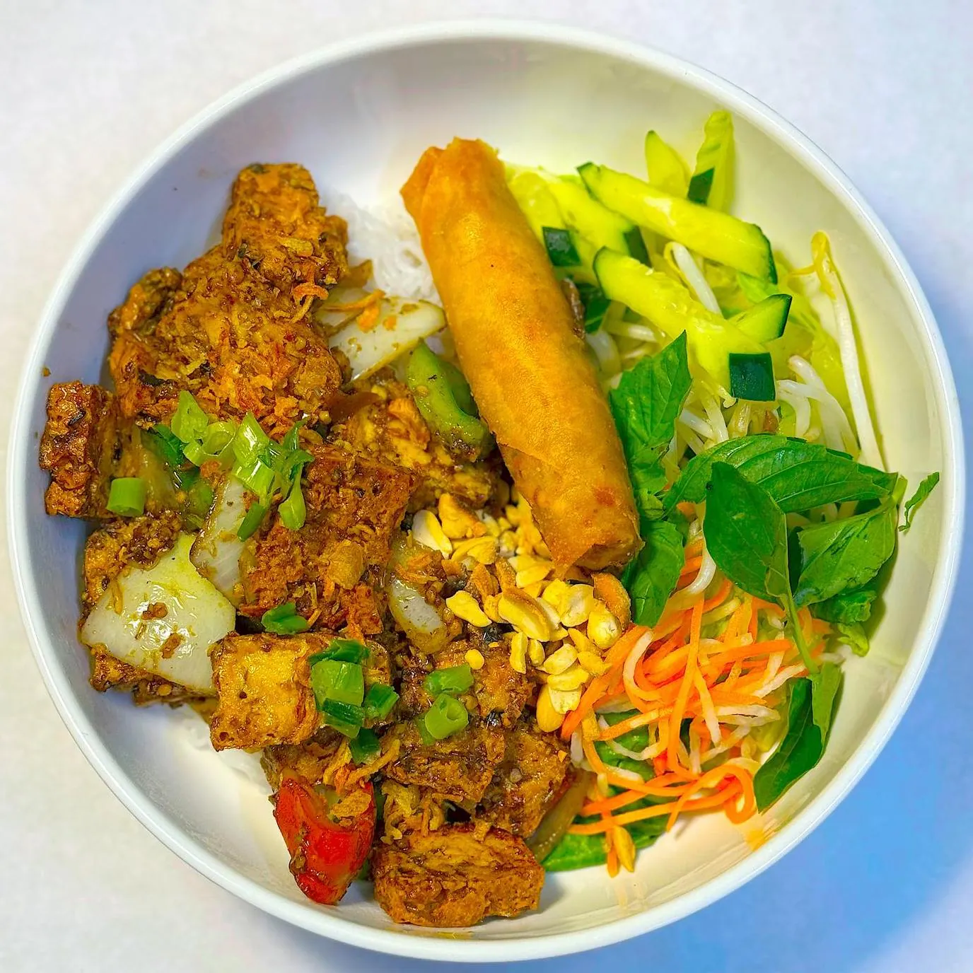 Curry tofu vermicelli bowl with egg roll and fresh veggies at Magnolia Pho, a Vietnamese Restaurant in Seattle